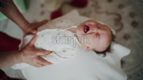 Baby placed on the back on a stability ball while adults support the infant's torso and shoulders