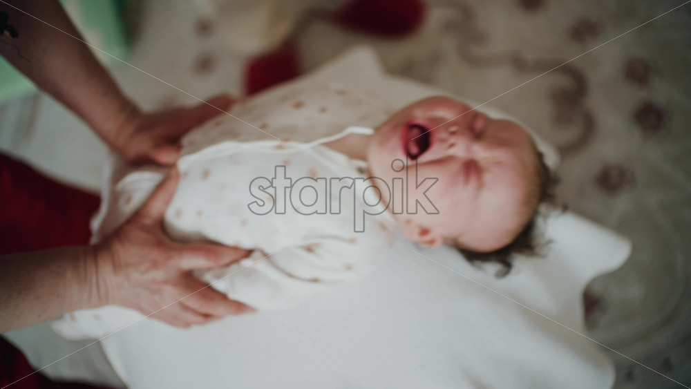 Baby placed on the back on a stability ball while adults support the infant's torso and shoulders