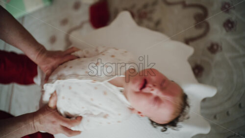 Baby placed on the back on a stability ball while adults support the infant's torso and shoulders
