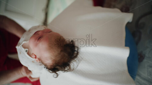 Baby placed on the back on a stability ball while adults support the infant's torso and shoulders