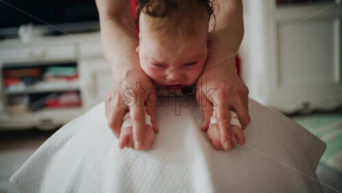 Baby placed on tummy on a stability ball while adults support the infant's torso and shoulders
