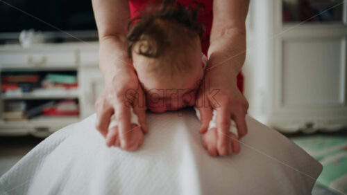 Baby placed on tummy on a stability ball while adults support the infant's torso and shoulders