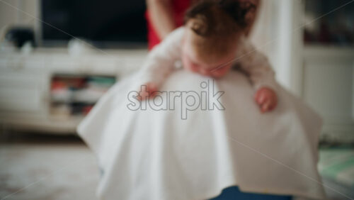 Baby placed on tummy on a stability ball while adults support the infant's torso and shoulders