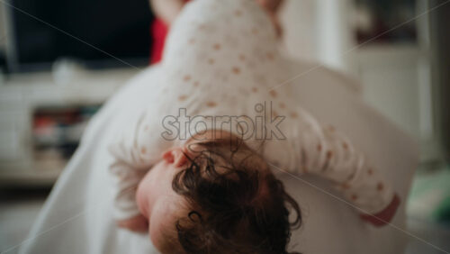 Baby placed on tummy on a stability ball while adults support the infant's torso and shoulders