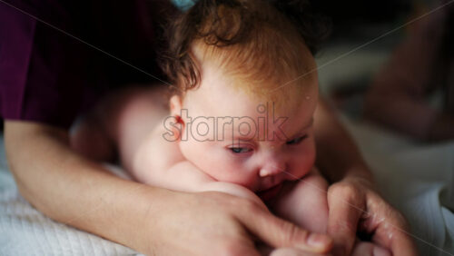 Baby lying on their tummy while an adult massages them and performs mobility exercises