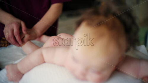 Baby lying on their tummy while an adult massages them and performs mobility exercises