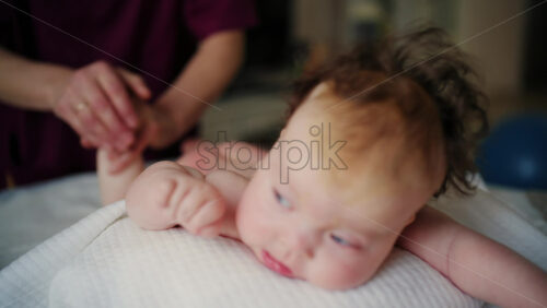 Baby lying on their tummy while an adult massages them and performs mobility exercises