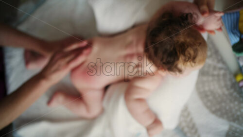 Baby lying on their tummy while an adult massages them and performs mobility exercises