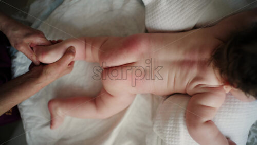 Baby lying on their tummy while an adult massages them and performs mobility exercises
