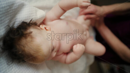 Baby lying on their back while an adult massages them and performs mobility exercises