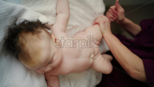 Baby lying on their back while an adult massages them and performs mobility exercises