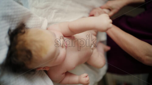 Baby lying on their back while an adult massages them and performs mobility exercises