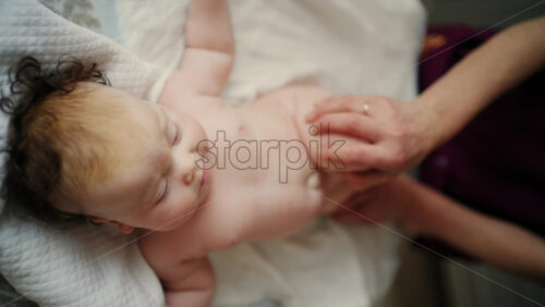 Baby lying on their back while an adult massages them and performs mobility exercises