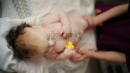 Baby lying on their back while an adult massages them and performs mobility exercises