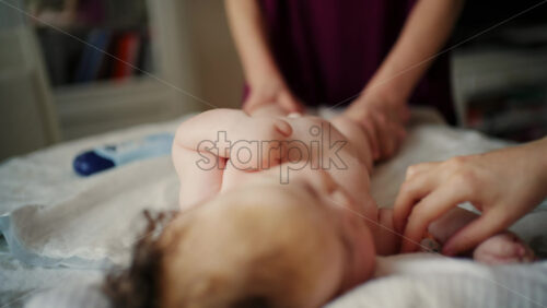Baby lying on their back while an adult massages them and performs mobility exercises