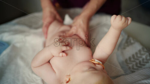 Baby lying on their back while an adult massages them and performs mobility exercises