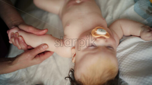 Baby lying on their back while an adult massages them and performs mobility exercises