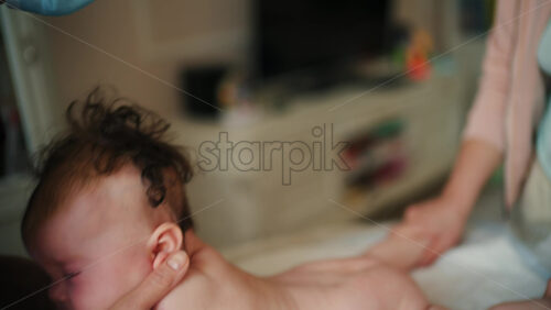 Caregiver doing mobility exercises with a baby, the mother is helping