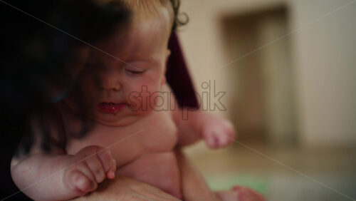 Baby sitting upright while being supported by an adult, showing effort and focus