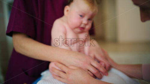 Baby sitting upright while being supported by an adult, showing effort and focus