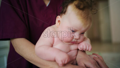Baby sitting upright while being supported by an adult, showing effort and focus