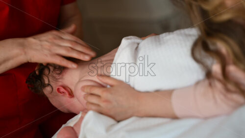 Close up of a baby lying on tummy while a caregiver gently massages the infant's head
