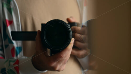 Close up of a man's hands holding a camera with a large lens, preparing to shoot