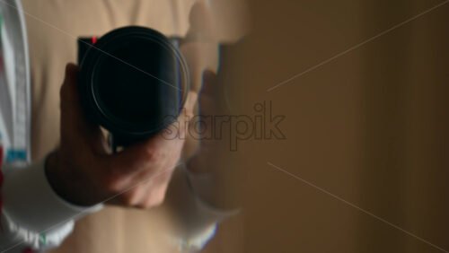 Close up of a man's hands holding a camera with a large lens, preparing to shoot
