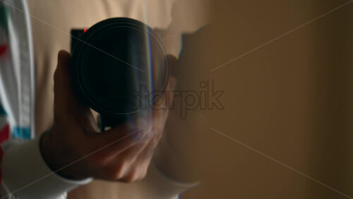 Close up of a man's hands holding a camera with a large lens, preparing to shoot