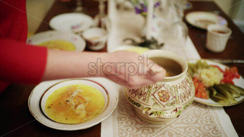 Close up of soup being scooped from a traditional ceramic serving pot