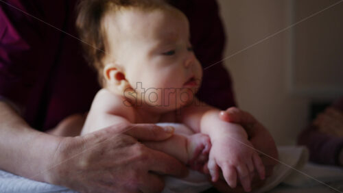 Baby lying on their tummy while an adult massages them and performs mobility exercises