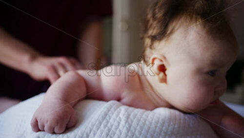 Baby lying on their tummy while an adult massages them and performs mobility exercises