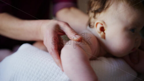 Baby lying on their tummy while an adult massages them and performs mobility exercises
