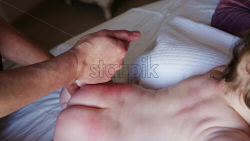 Close up of a caregiver holding a baby's small foot while tending to the infant on a bed