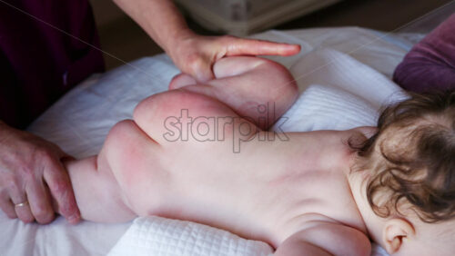 Close up of a caregiver holding a baby's small foot while tending to the infant on a bed