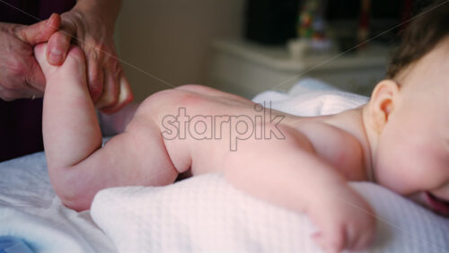 Close up of adult hands gently massaging a baby's foot and sole