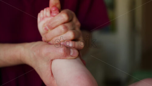 Close up of adult hands gently massaging a baby's foot and sole