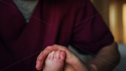 Close up of adult hands gently massaging a baby's foot and sole