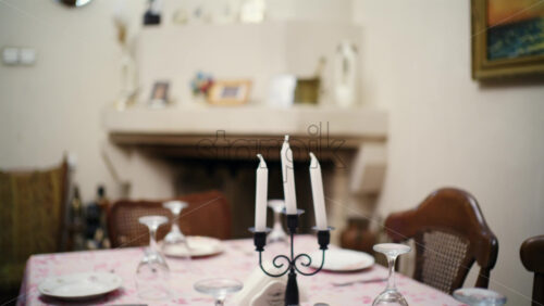 Dining table set with plates, glasses, and white candles in a cozy home interior