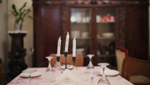 Dining table set with plates, glasses, and white candles in a cozy home interior