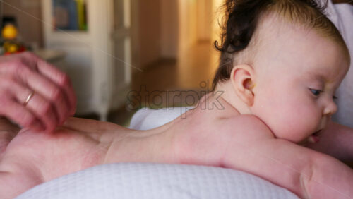 Baby lying on their tummy while an adult massages them and performs mobility exercises