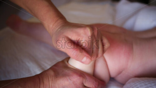 Close up of adult hands gently massaging a baby's foot and sole
