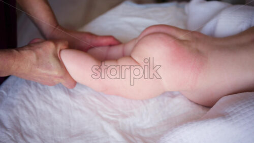 Baby lying on their tummy while an adult massages them and performs mobility exercises