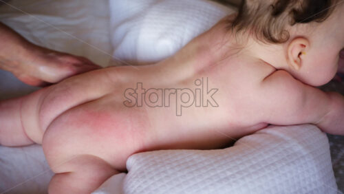 Baby lying on their tummy while an adult massages them and performs mobility exercises