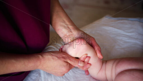 Close up of adult hands gently massaging a baby's foot and sole