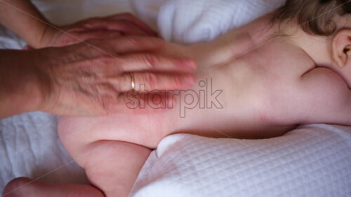 Baby lying on their tummy while an adult massages them and performs mobility exercises