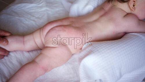Baby lying on their tummy while an adult massages them and performs mobility exercises