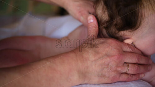 Baby lying on their tummy while an adult massages them and performs mobility exercises