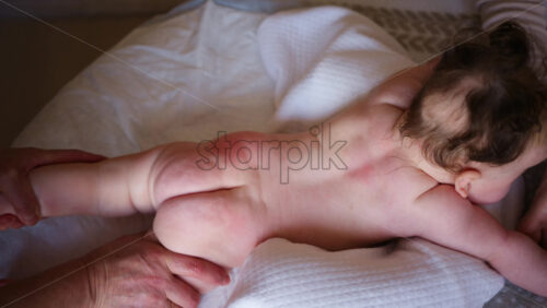 Baby lying on their tummy while an adult massages them and performs mobility exercises