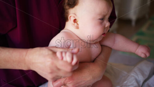 Close up of caregiver supporting a baby's arms and upper body during assisted movement